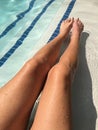 Young womanÃ¢â¬â¢s long tan legs in bright blue pool water Royalty Free Stock Photo